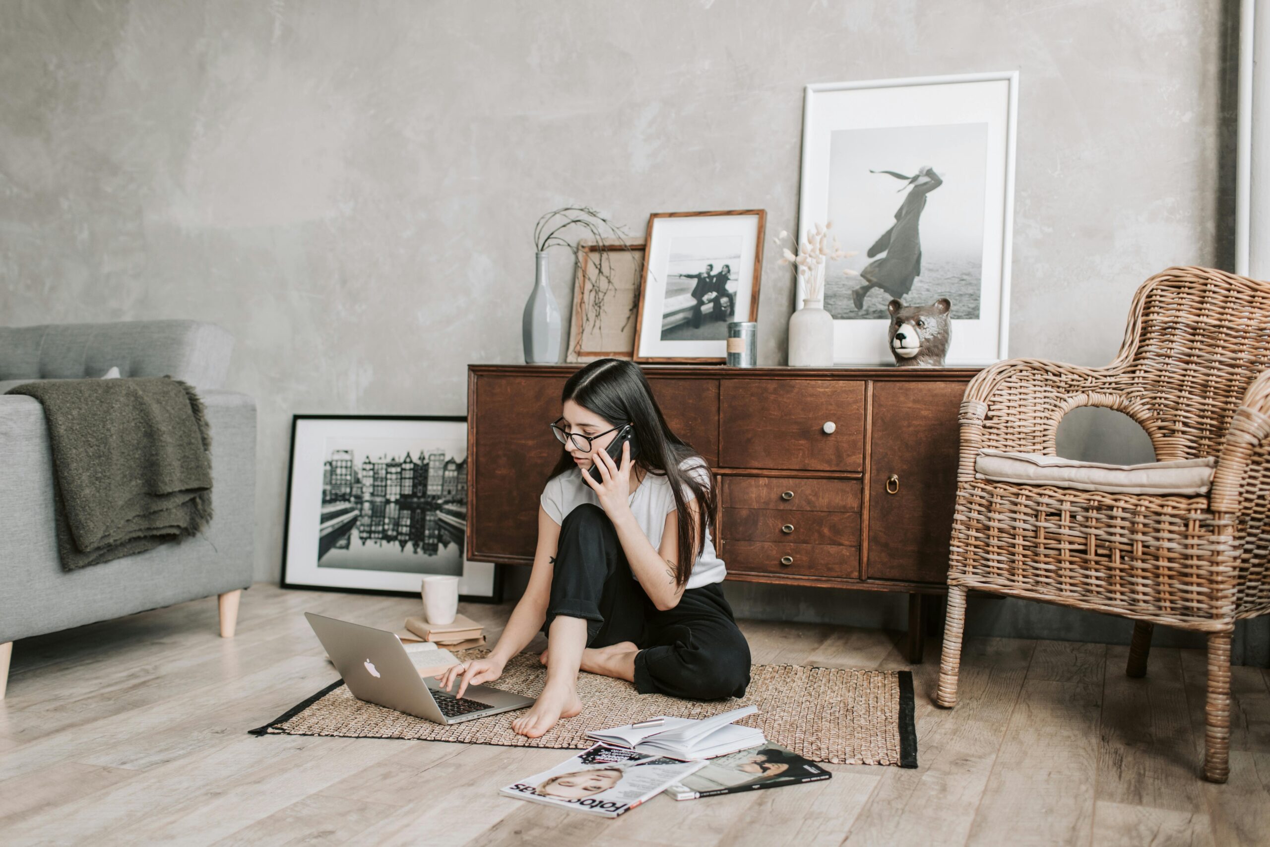 Woman using a laptop and phone in a modern, stylish living room with artistic decor.